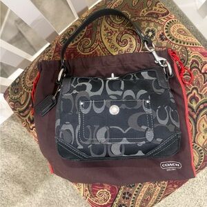 Small black Coach bag with woven print and unique closure.